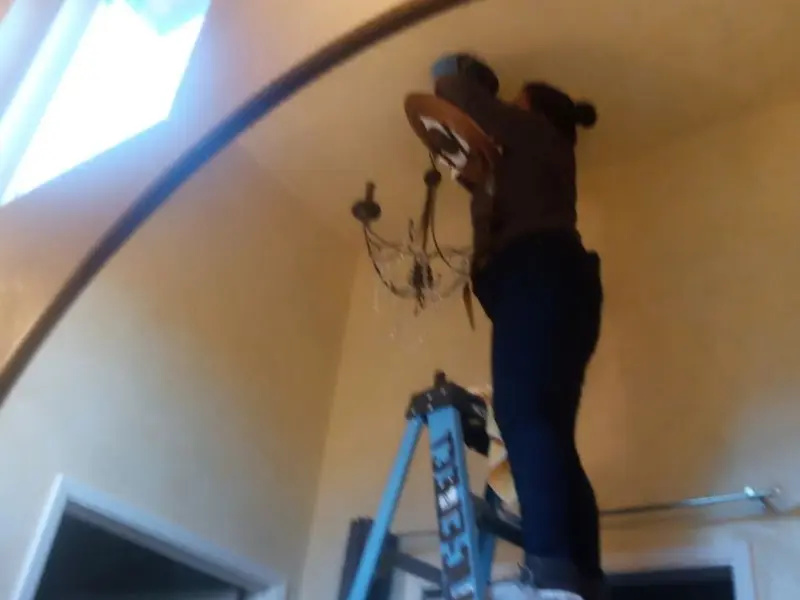 Electrician installing a chandelier in a Taylor Creek residence